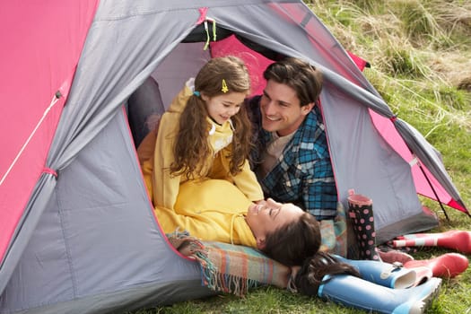 Young Family Relaxing Inside Tent On Camping Holiday