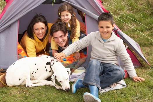 Young Family With Dog Relaxing Inside Tent On Camping Holiday