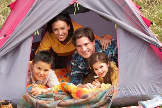 Young Family Relaxing Inside Tent On Camping Holiday