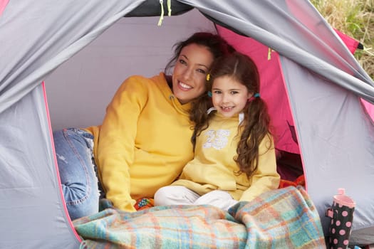 Mother And Daughter Relaxing Inside Tent On Camping Holiday