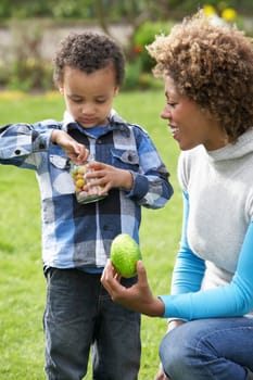 Mother Helping Son To Unwrap Chocolate Easter Egg