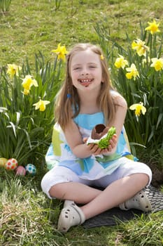 Girl Eating Chocolate Egg On Easter Egg Hunt In Daffodil Field