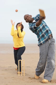 Young Couple Playing Cricket On Autumn Beach Holiday