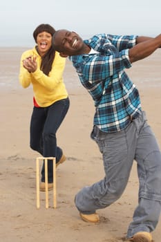 Young Couple Playing Cricket On Autumn Beach Holiday