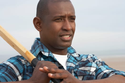 Young Man Playing Cricket On Autumn Beach Holiday