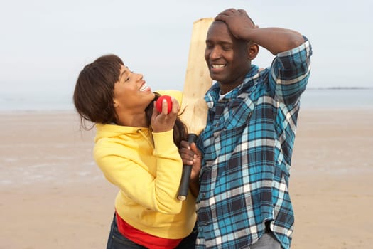 Young Couple Playing Cricket On Autumn Beach Holiday