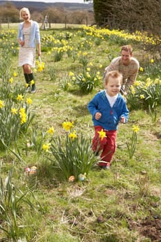 Family On Easter Egg Hunt In Daffodil Field