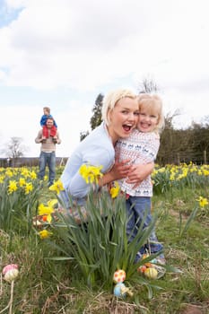 Family On Easter Egg Hunt In Daffodil Field