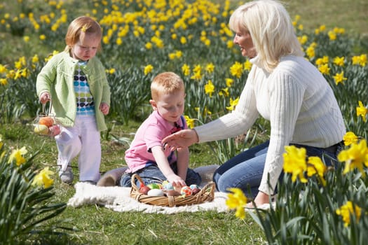 Mother And Children In Daffodil Field With Decorated Easter Eggs