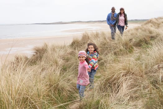 Family Walking Along Dunes On Winter Beach