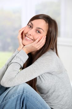 Smiling young woman at home sitting on sofa