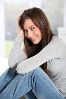 Smiling young woman at home sitting on sofa