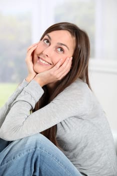 Smiling young woman at home sitting on sofa