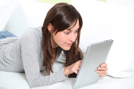 Young woman sitting on sofa with electronic pad