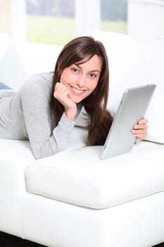 Young woman sitting on sofa with electronic pad