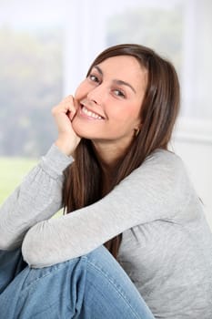 Smiling young woman at home sitting on sofa