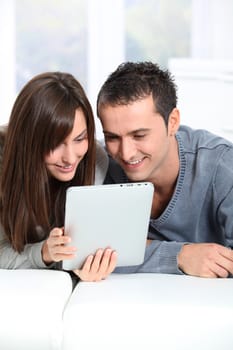 Couple sitting on sofa with electronic pad