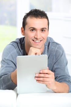 Young man sitting on sofa with electronic pad