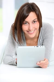 Young woman laying on sofa with electronic pad