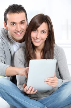 Young couple sitting on sofa with electronic pad