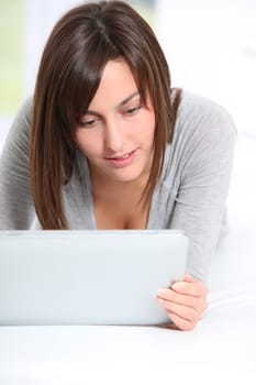 Young woman laying on sofa with electronic pad