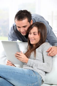 Couple sitting on sofa with electronic pad