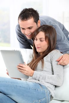 Couple sitting on sofa with electronic pad
