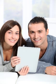 Couple sitting on sofa with electronic pad