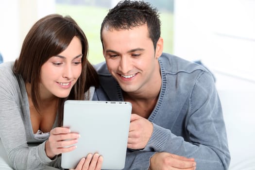 Couple sitting on sofa with electronic pad