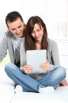 Young couple sitting on sofa with electronic pad