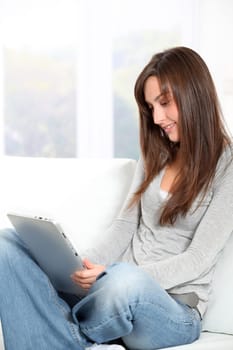 Young woman sitting on sofa with electronic pad