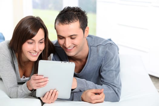 Couple sitting on sofa with electronic pad