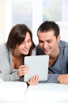 Couple sitting on sofa with electronic pad