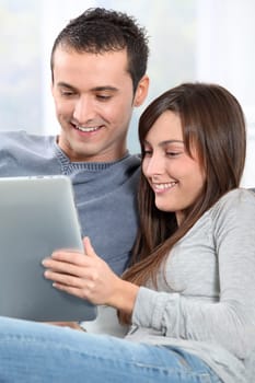 Couple sitting on sofa with electronic pad