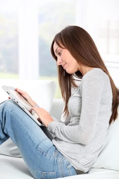 Young woman sitting on sofa with electronic pad