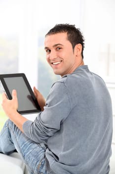 Young man sitting on sofa with electronic pad
