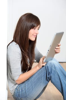 Young woman sitting on the floor with electronic pad