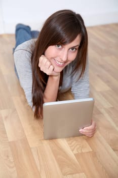Young woman laying down the floor with electronic pad