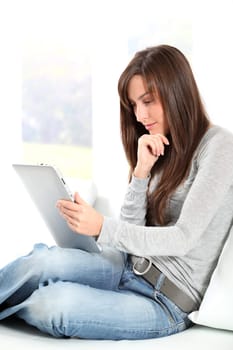 Young woman sitting on sofa with electronic pad