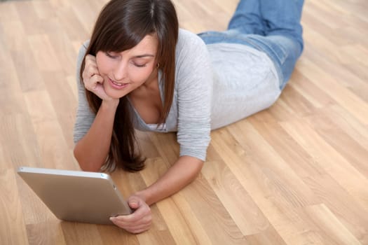 Young woman laying down the floor with electronic pad