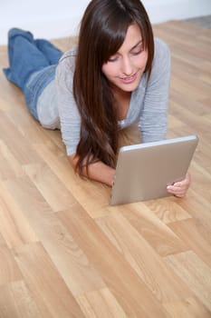 Young woman laying down the floor with electronic pad