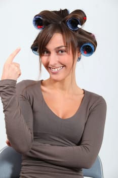 Beautiful woman with hair-curlers doing funny faces