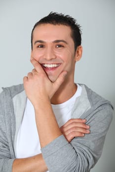 Closeup of young man smiling with hand on chin