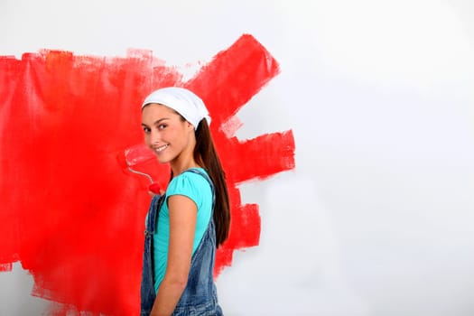 Young woman painting house wall in red