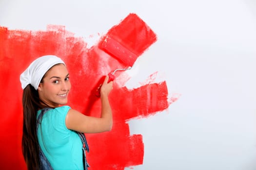 Young woman painting house wall in red