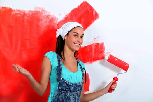 Young woman painting house wall in red