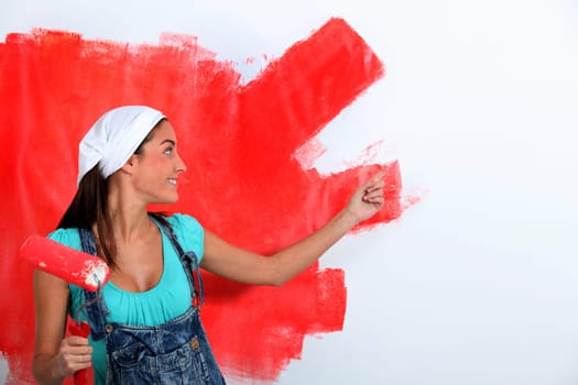 Young woman painting house wall in red