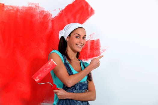 Young woman painting house wall in red