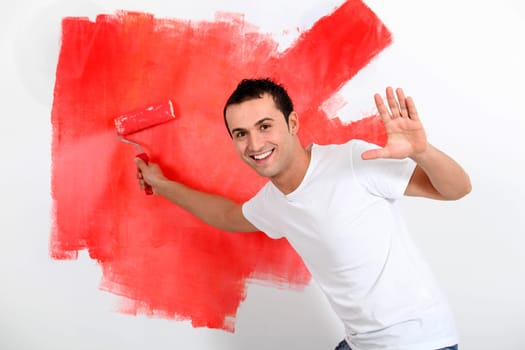 Young man painting house wall in red