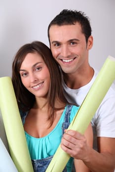 Closeup of young couple holding wallpaper rolls